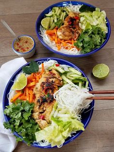 two blue bowls filled with food on top of a wooden table