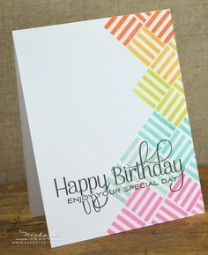 a card with the words happy birthday written in rainbow colors on it, sitting on top of a wooden table