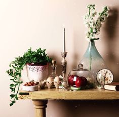 a wooden table topped with vases filled with flowers and other items next to a candle