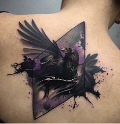 the back of a woman's shoulder with a bird and triangle tattoo on it