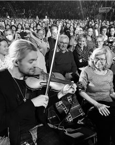 a black and white photo of a man playing the violin in front of an audience