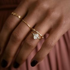 a woman's hand wearing a gold ring with a diamond on the middle finger