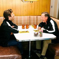 two men sitting at a table talking to each other