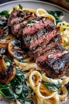 a plate with pasta, mushrooms and spinach on it