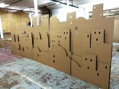 cardboard cut out buildings sitting on top of a floor in an unfinished building with windows and doors