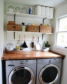 a washer and dryer in a small room with open shelving on the wall