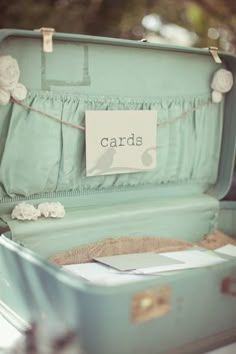 an open suitcase sitting on top of a wooden floor next to a sign that says cards