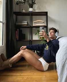 a man sitting on the floor taking a selfie with his phone and headphones