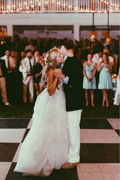 a bride and groom dance together in front of a large group of people at their wedding reception