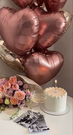 a bunch of balloons that are sitting on a table next to a cake and flowers