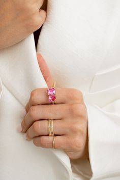 a woman's hand wearing a gold ring with pink stones