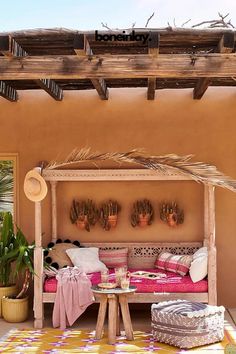 an outdoor area with a bench, potted plants and pillows