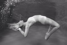 a woman in white swimsuit diving under water