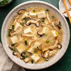 a bowl of soup with tofu, mushrooms and green onions