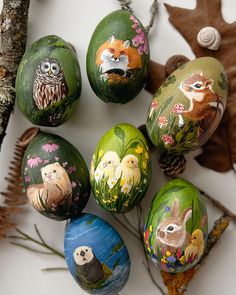 an arrangement of painted rocks with animals and plants on them, including pineconi