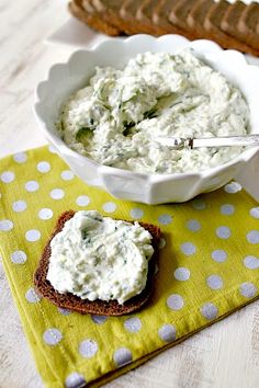 a bowl of dip next to a sandwich on a yellow napkin