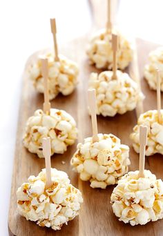 caramel popcorn balls are arranged on a cutting board with toothpicks in them