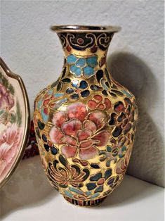 two vases sitting next to each other on a table with flowers painted on them