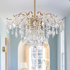 a chandelier hanging from the ceiling in a living room with blue walls and furniture