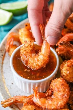 a person dipping sauce onto shrimp on a plate