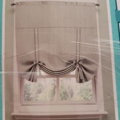 an open window with a curtain and valance on the top, in front of a blue wall