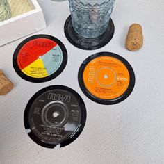 three different colored records sitting on top of a table next to a glass and cork