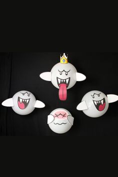 four white balls with mouths and crowns on them, one is sticking out its tongue