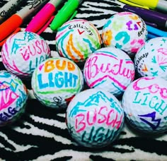 many different colored balls with writing on them next to markers and crayon pens