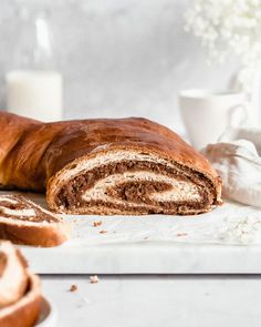 a loaf of cinnamon swirl bread sitting on top of a counter next to a glass of milk