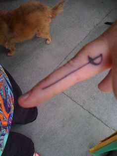 a person with a small tattoo on their finger pointing at a dog that is standing next to them