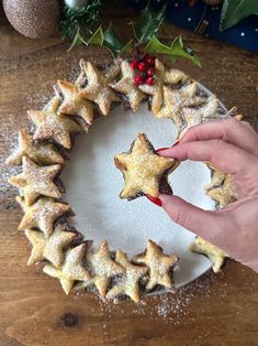 a person holding a star shaped cookie in front of a christmas wreath on a table