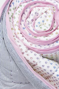 the pink and white scarf is folded up on top of striped shirting, with hearts all over it