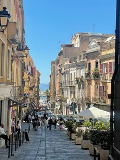 people are walking down the street in an old town with many buildings on both sides