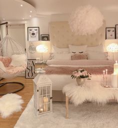 a bedroom decorated in pink and white with hanging lights, fur rugs, chandelier