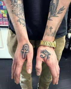 two hands with tattoos and an egyptian symbol on them, both holding their fingers together