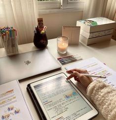 a person sitting at a desk with an ipad and notebook in front of them, holding a pen