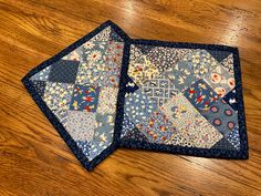 two quilted coasters sitting on top of a wooden table