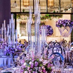 a table set up with purple flowers and silverware for an elegant wedding or reception