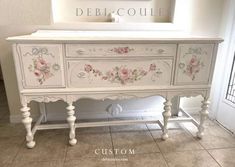 a white dresser with pink flowers painted on the top and bottom, sitting in a room