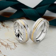 two silver and gold wedding rings sitting next to each other on top of a table