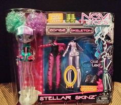 two dolls are in the packaging for their new toys, one is pink and one is green