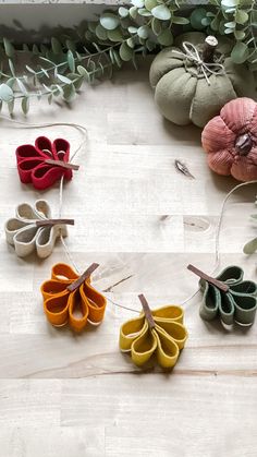 several small pieces of fabric hanging from strings on a table with greenery in the background