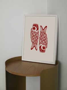 two red fish are sitting on top of a wooden table next to a white wall