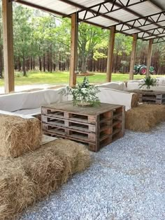 an outdoor area with hay bales on the ground and tables made out of wooden pallets