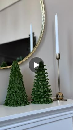 a white mantle topped with christmas trees next to a mirror and candle holder on top of a dresser