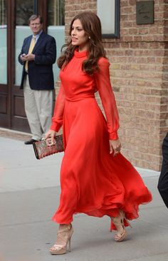 a woman in a red dress is walking down the street