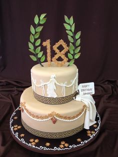 a three tiered cake is decorated with gold and green leaves on the top layer