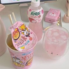 a pink cup with straws in it sitting on a desk next to a computer