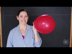 a woman holding a red balloon in front of a blackboard