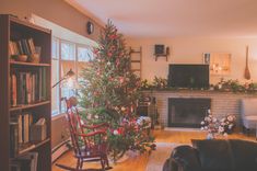 a living room with a christmas tree in the corner and other decorations on the fireplace